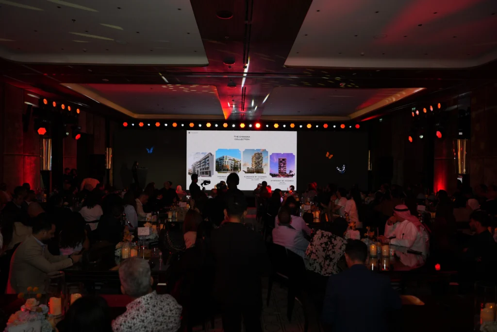 Chaimaa Collection real estate launch event at Bvlgari Hotel Dubai with an engaged audience, property presentation on a large LED screen and warm red ambient lighting