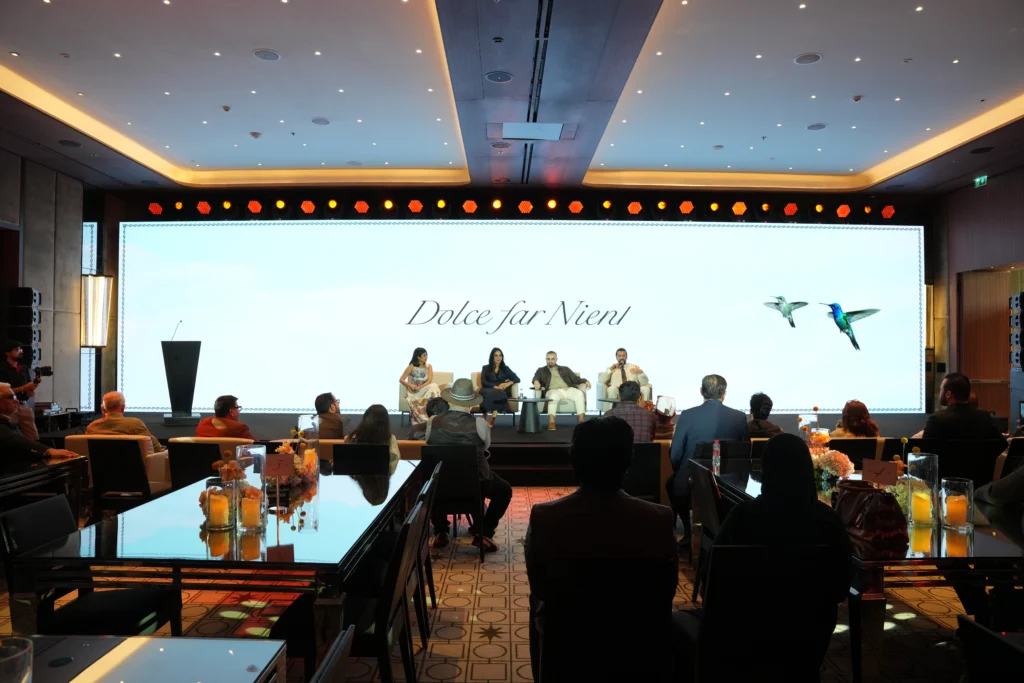 Dolce Far Niente brand panel discussion at Bvlgari Hotel Dubai with four panelists seated on stage in front of a large elegant LED backdrop and an intimate audience