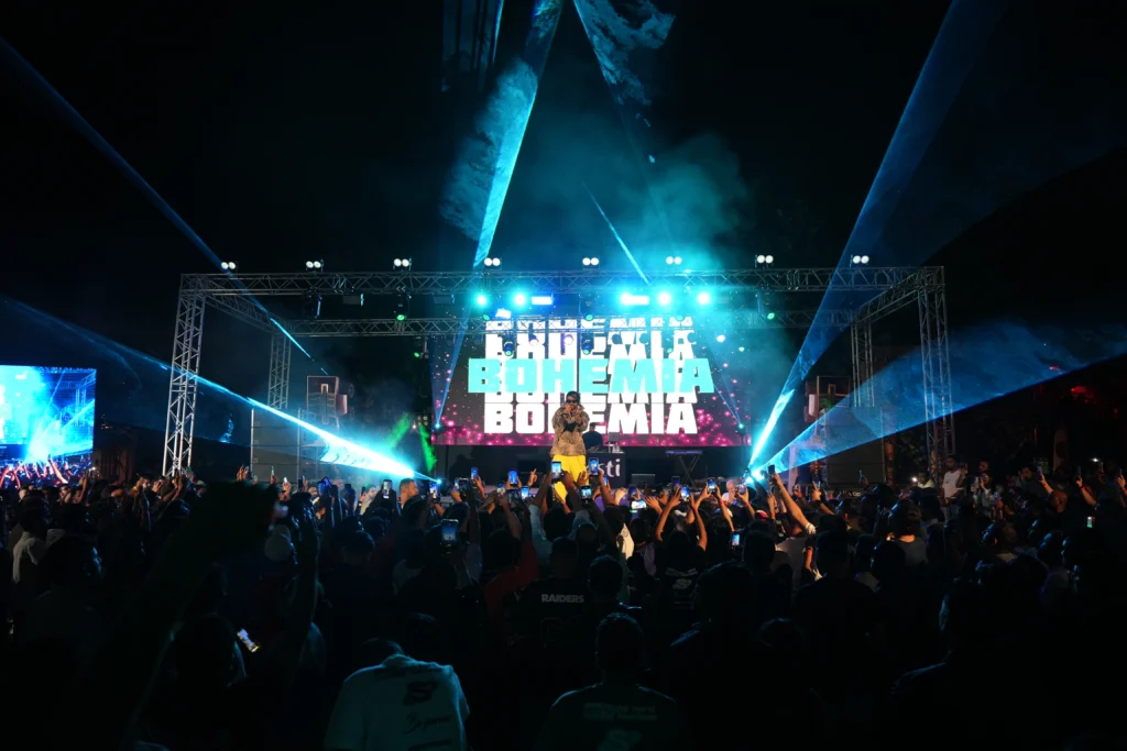 Bohemia live concert at Barasti Beach Dubai with hundreds of fans raising hands and phones under dramatic cyan laser beams and LED stage lighting