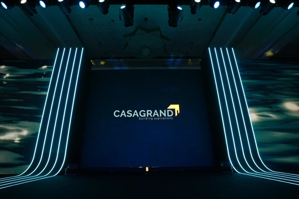 Casagrand Building Aspirations branded corporate event stage with sleek neon light lines and a navy blue LED screen backdrop