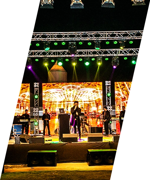 A live band performing on an outdoor event stage with colorful stage lighting, LED backdrop and professional sound equipment at a night event