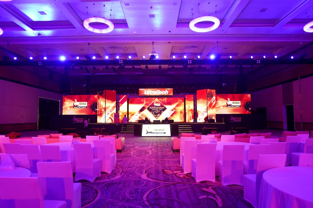 UltraTech Cement Abhinandan Awards ceremony stage in Abu Dhabi with a bold red and gold branded LED backdrop and purple ambient lighting in a grand ballroom